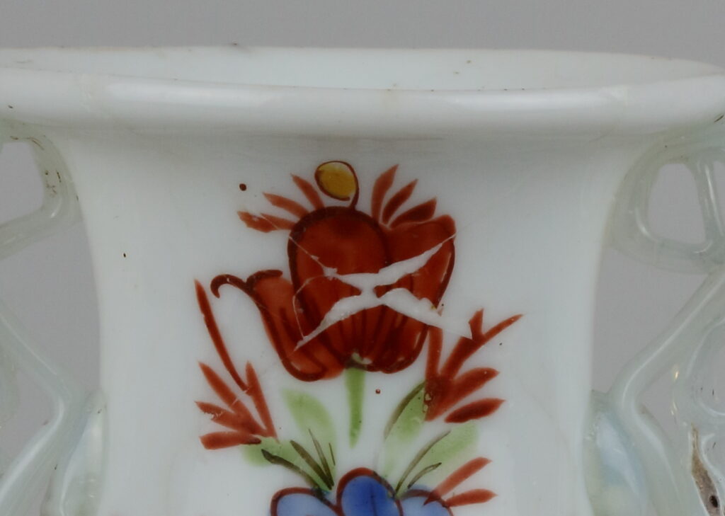 Detail van het vaasje uit de 18e eeuw dat de kleine lacunes toont die na het verlijmen van de scherven nog zichtbaar zijn.